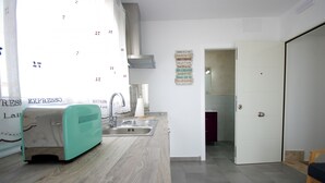 Een keuken met een spoelbak, een aanrecht, een broodrooster en een deur naar een andere kamer.