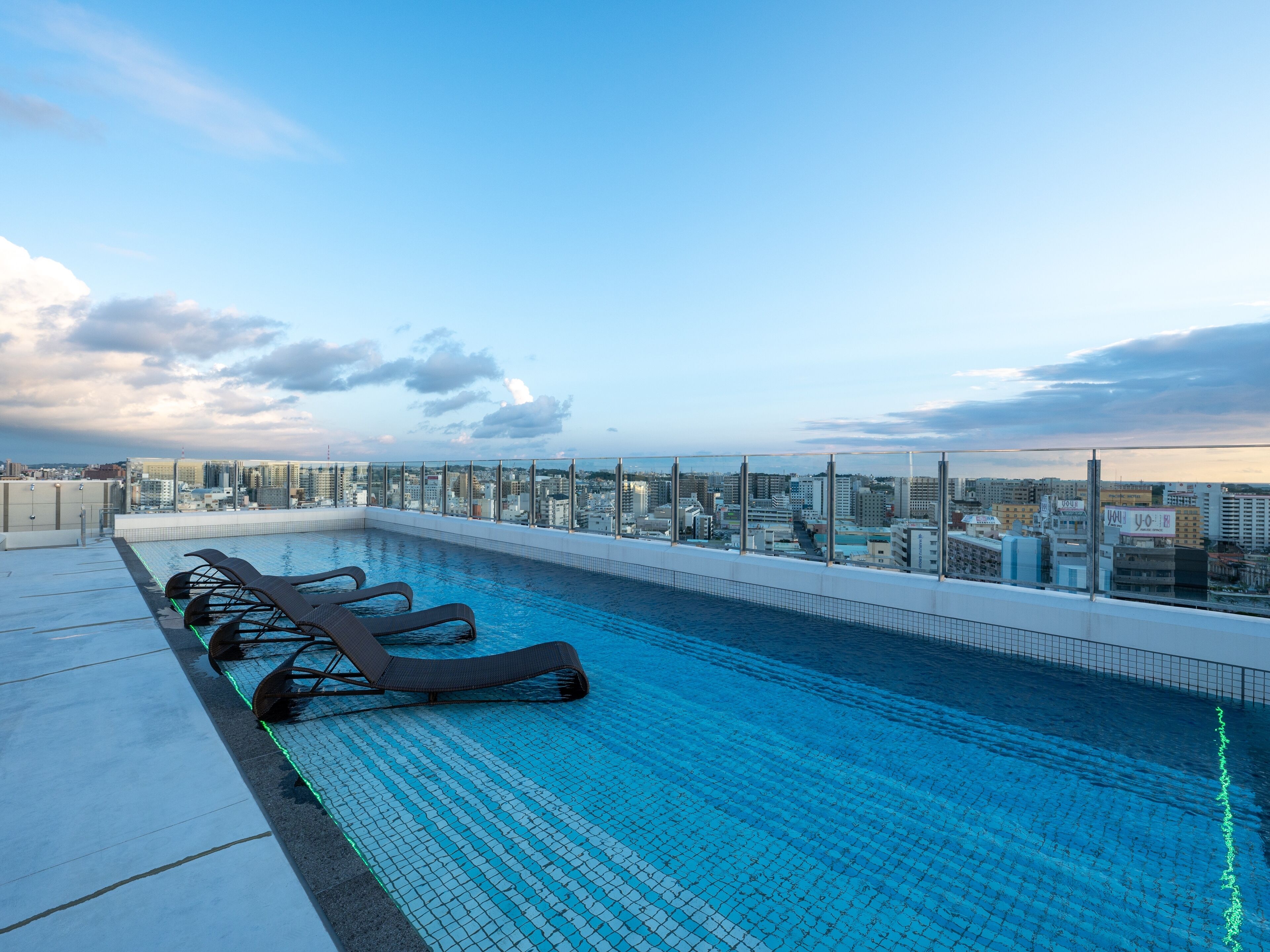 Una piscina en la azotea con sillas de descanso y vistas a la ciudad.