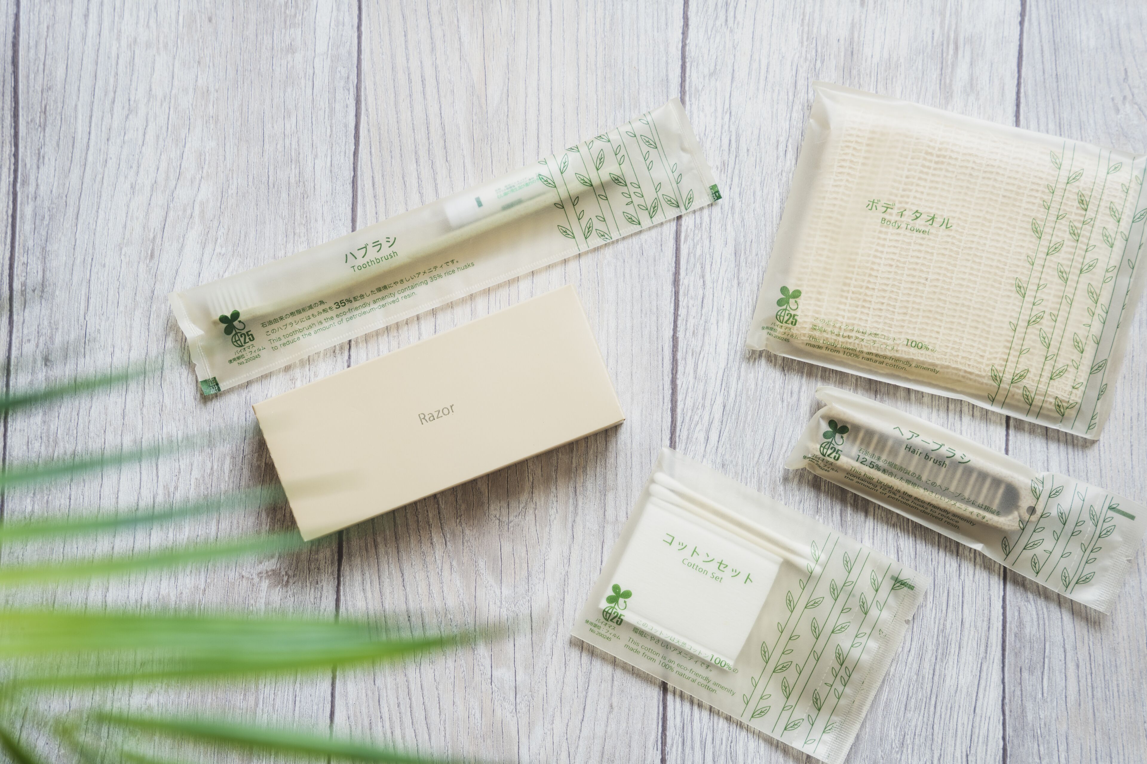 A set of personal care items including a razor, body towel, hair brush, and cotton set on a wooden surface.