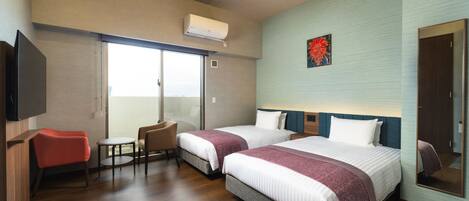 A hotel room with two beds, a TV, a small table, a chair, and a sliding glass door to the balcony.