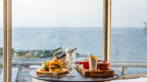 Una mesa con comida, un vaso y vistas al mar.