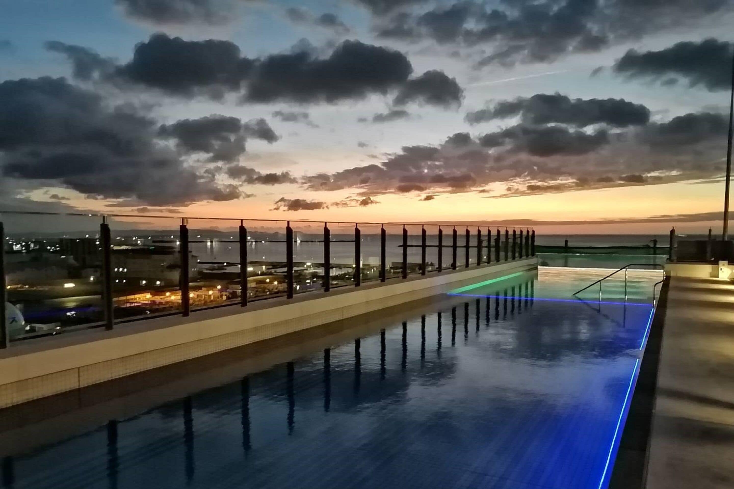 A rooftop pool with a view of the city skyline at sunset.