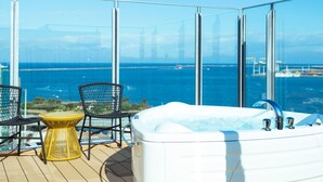 Un balcón con un jacuzzi, dos sillas y una mesita.