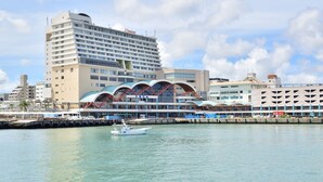 Un hotel frente al agua con un diseño moderno, que presenta un edificio grande con varios pisos y una estructura curva distintiva al frente.