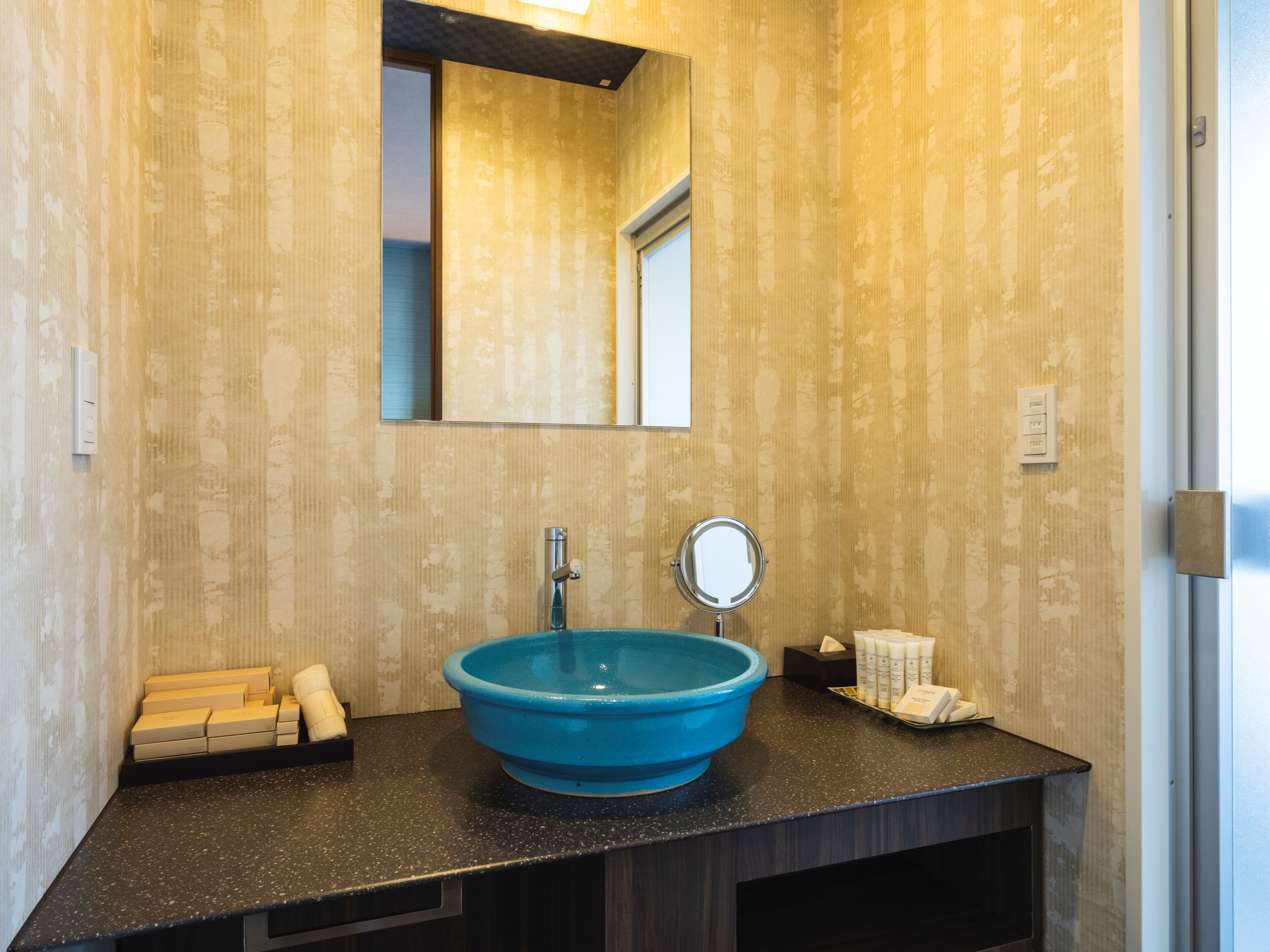 A bathroom with a blue sink, a mirror, and a towel rack.