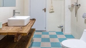 A bathroom with a wooden vanity, white sink, and a shower with a handheld showerhead. - Floral Hotel He Ping He Yuan Jixian (Tianjin)