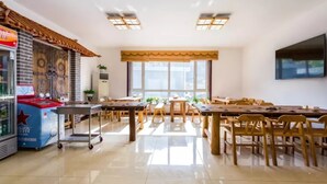 A dining area with wooden tables and chairs, a vending machine, and a large window providing natural light. - Floral Hotel He Ping He Yuan Jixian (Tianjin)