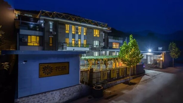 A modern hotel with a well-lit entrance, a gated area, and a signboard. - Floral Hotel He Ping He Yuan Jixian (Tianjin)