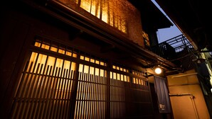 A traditional Japanese building with a wooden gate and a lit interior, suggesting a warm, inviting atmosphere. - Kanade Matsubaragokomachi (Kyoto)