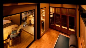 A traditional Japanese-style room with tatami flooring, a low wooden table, and a futon bed. - Kanade Matsubaragokomachi (Kyoto)