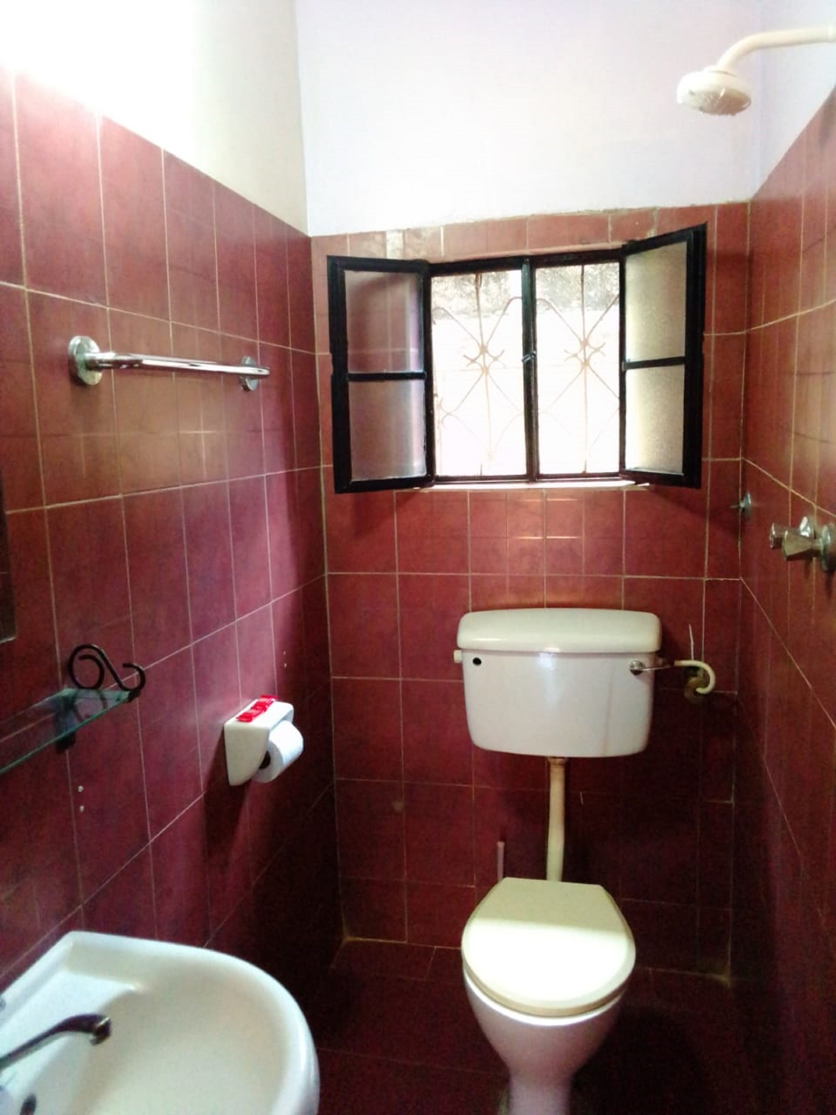 Une petite salle de bain avec des toilettes, un lavabo et une fenêtre.