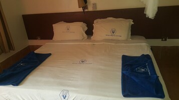 A hotel room with a neatly made bed, two pillows, and two towels.