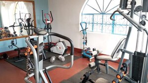 Une salle de sport équipée de divers appareils d’exercice, notamment un tapis de course, des appareils de musculation et des haltères.