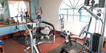 A gym with various exercise equipment, including a treadmill, weight machines, and dumbbells.