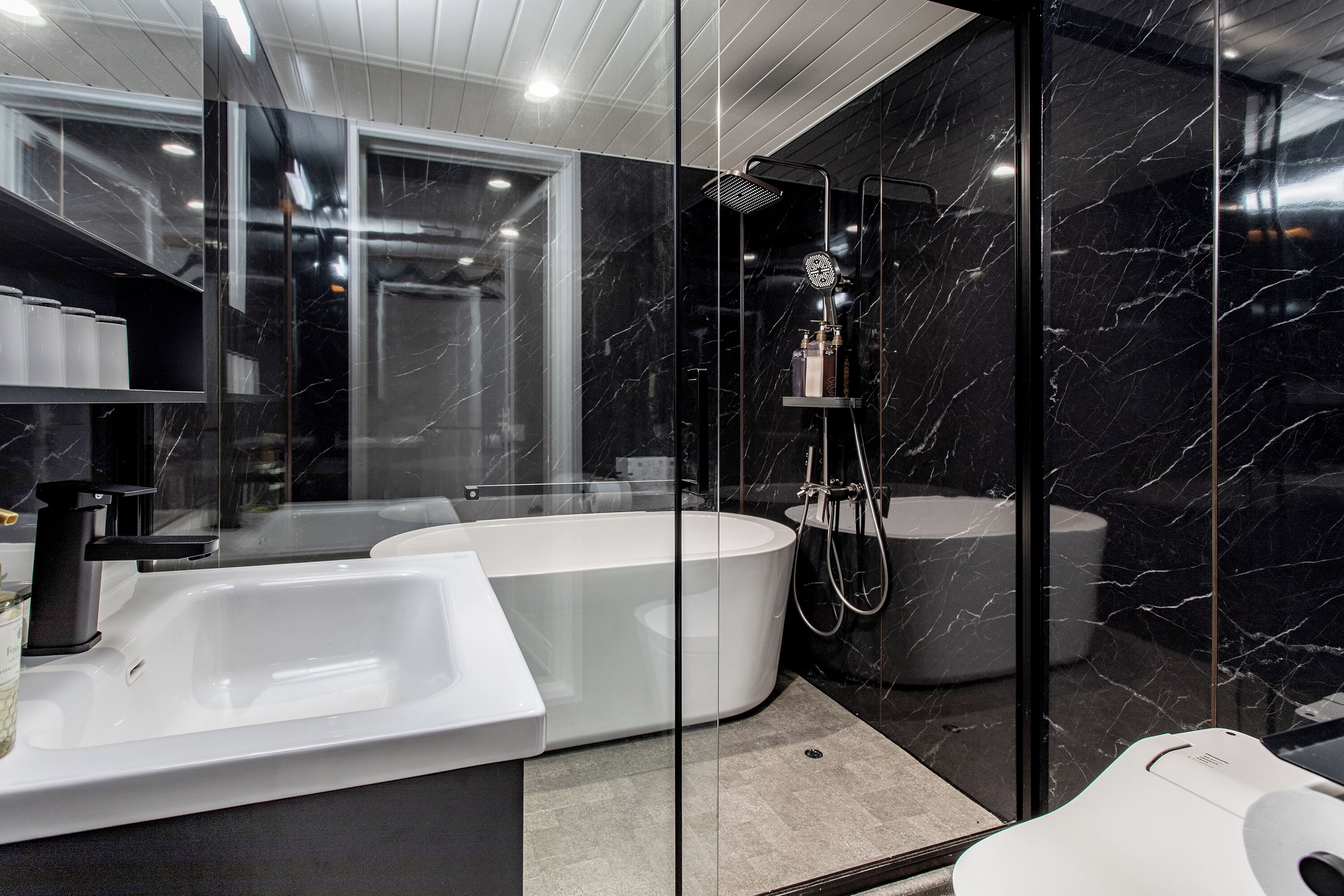 Une salle de bain moderne avec une baignoire blanche, un espace douche séparé et un meuble-lavabo avec un encadrement en verre.