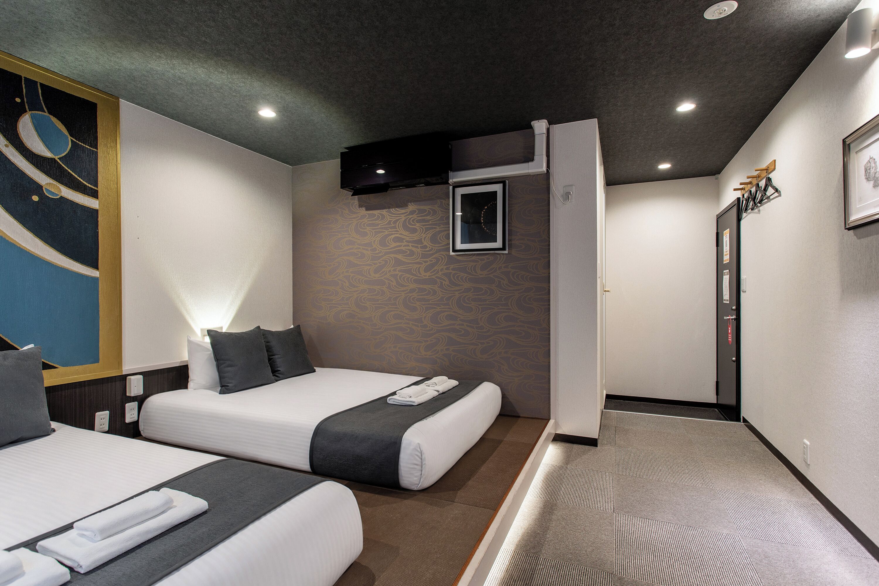A hotel room with two beds, a large abstract painting on the wall, and a modern design.