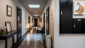 Un couloir d’hôtel avec des œuvres d’art encadrées, un comptoir de réception, un espace salon et une poubelle.