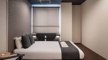 Habitación de hotel moderna con una cama grande, lámparas de noche, un escritorio con teléfono y una ventana con persianas.
