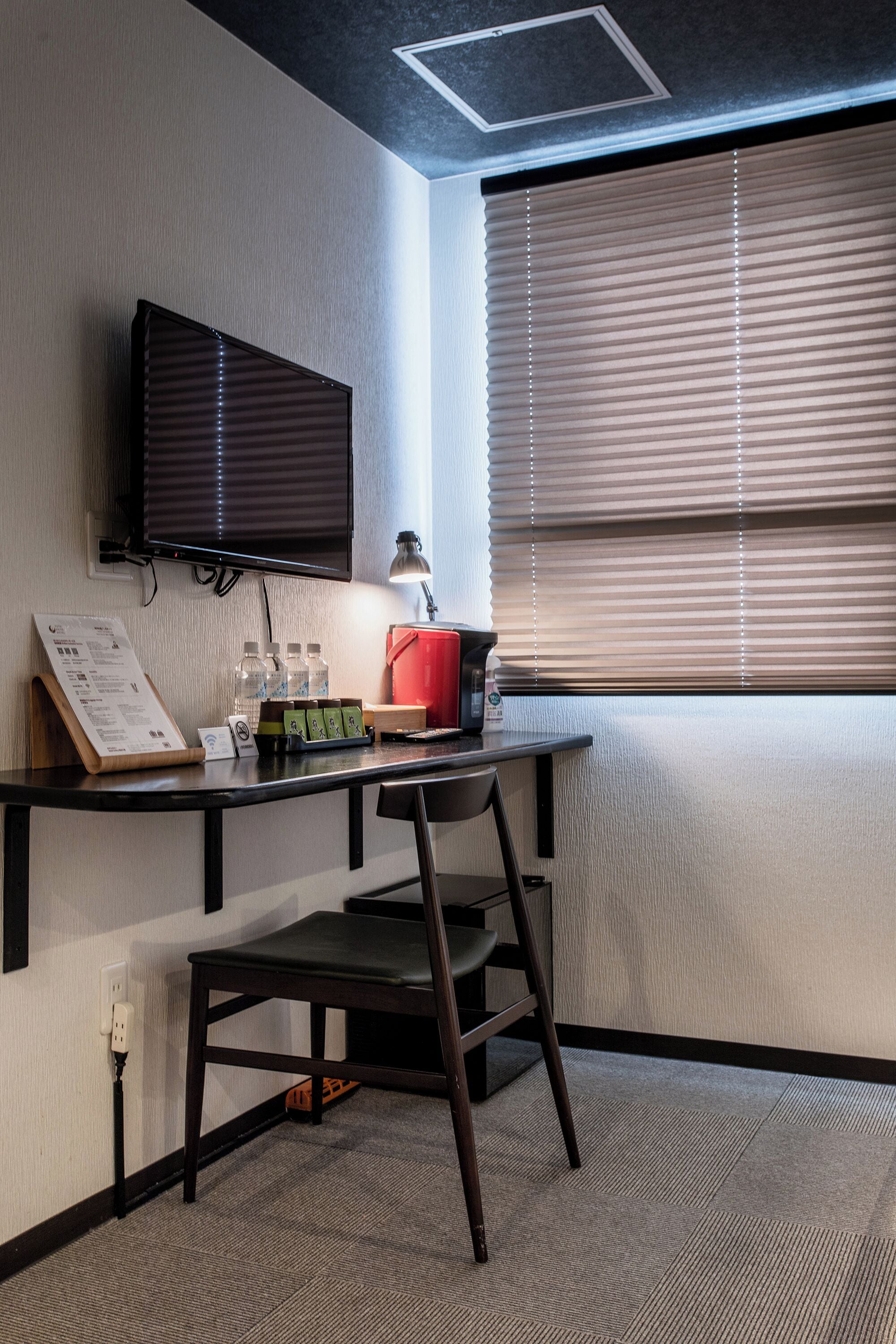 Un espacio de oficina moderno con un escritorio, una silla y un televisor de pantalla plana montado.