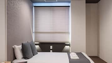 A modern bedroom with a bed, bedside table, chair, and a window with blinds.