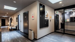 Un couloir d’hôtel avec un espace détente, des portes et une poubelle.