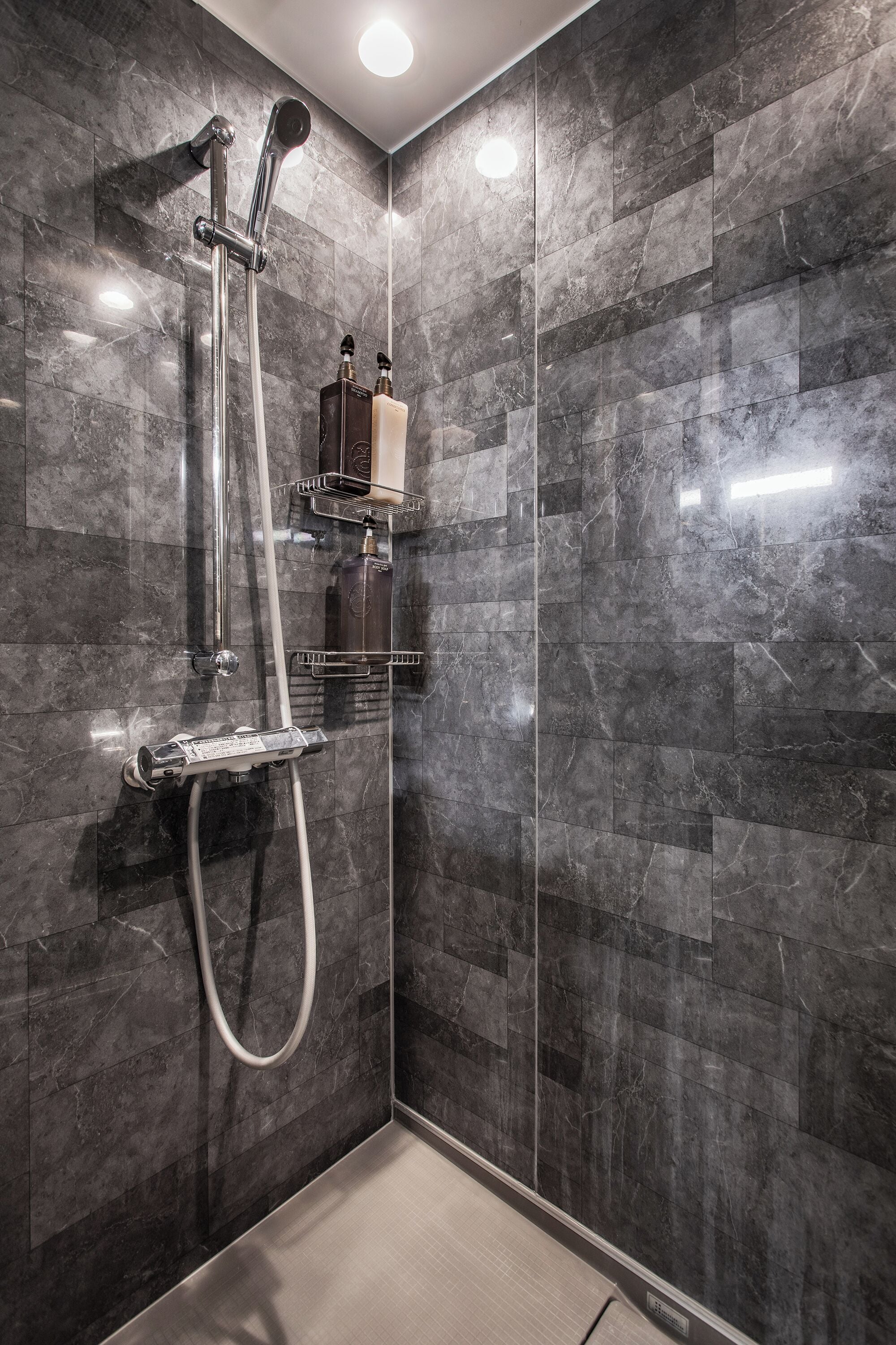 A walk-in shower with a glass door, a handheld showerhead, and a handheld shower attachment.