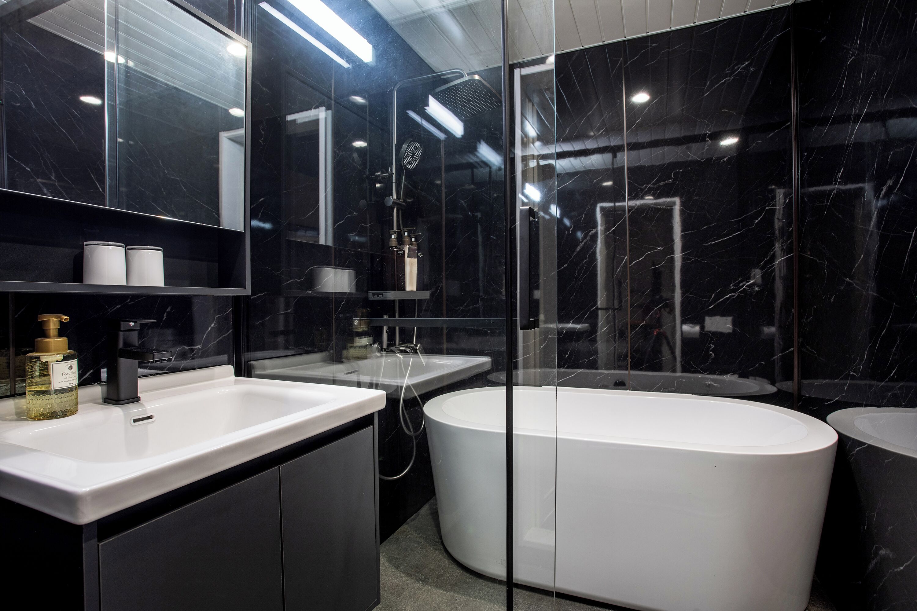 A modern bathroom with a large bathtub, a separate sink, and a mirror above the sink.