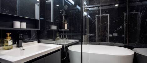 A modern bathroom with a large bathtub, a separate sink, and a mirror above the sink.