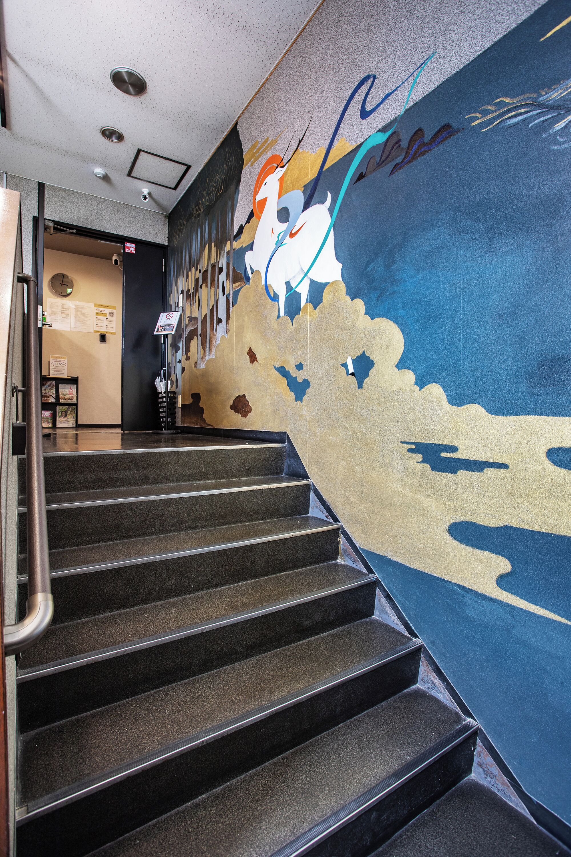 Una escalera con barandilla que conduce a una habitación con un mural en la pared.
