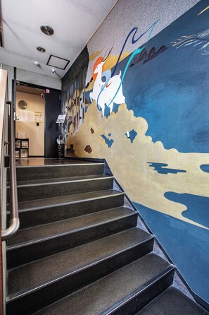 Una escalera con barandilla que conduce a una habitación con un mural en la pared.