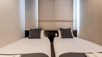 Habitación de hotel con dos camas, una ventana con persianas y una pared con diseño.