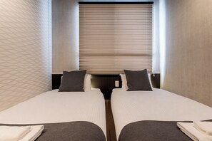 Habitación de hotel con dos camas, una ventana con persianas y una pared con diseño.