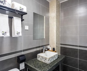 A modern bathroom with a granite countertop, a white sink, and a mirror above it. There are towels hanging on a rack and a paper towel dispenser on the wall. - Floral Hotel Splendid Valley Beijing (Beijing)