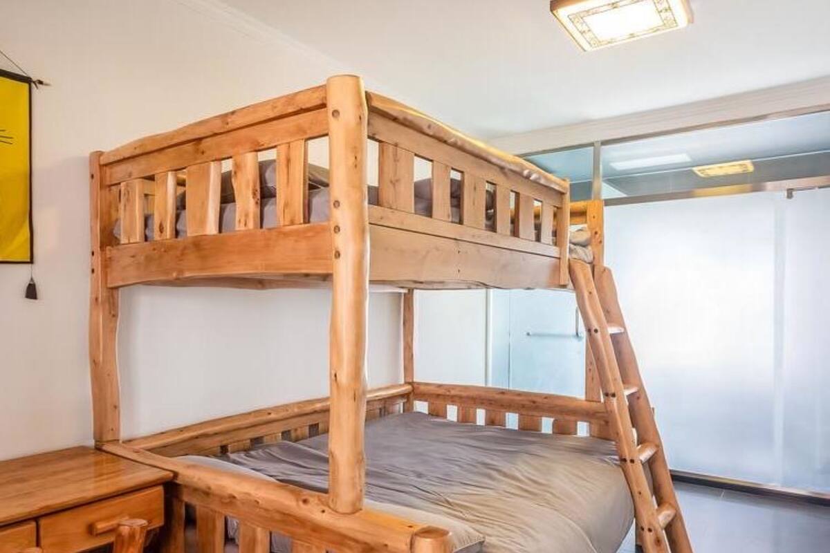 A bunk bed with a wooden frame, a desk, and a ladder.