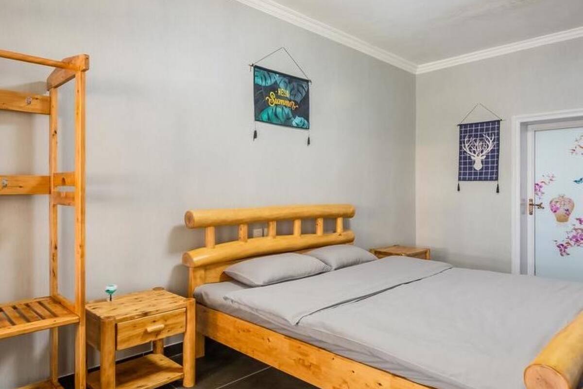 A single wooden bed with a headboard, a nightstand, and a small wooden table.