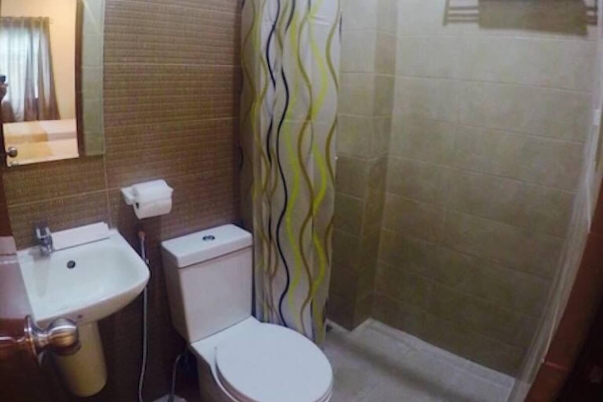 Un baño con ducha, inodoro, lavamanos y toallero.