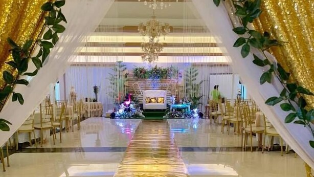 A venue with a central aisle leading to a stage, surrounded by chairs and a floral arrangement. - Nathaniel Hotel (Daet)