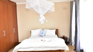A bedroom with a bed, a wardrobe, and a mosquito net. - Valbras Homestay Nairobi (Syokimau)
