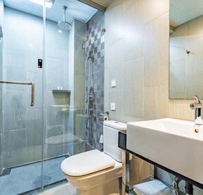 A modern bathroom with a glass-enclosed shower, a toilet, and a sink with a mirror. - Floral Hotel The Upper House Pingle (Chengdu)