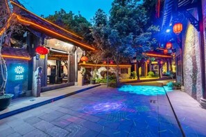A courtyard with a pool, traditional architecture, and illuminated signage. - Floral Hotel The Upper House Pingle (Chengdu)