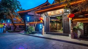 A traditional building with a sign in a foreign language, surrounded by trees and illuminated by warm lights.