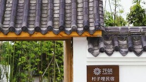 A traditional Chinese roof with a wooden overhang and a signboard indicating a hotel named 'CUN ZI LI'.