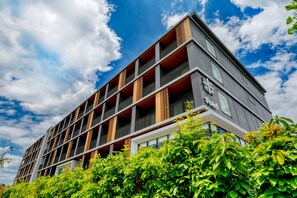 A modern multi-story building with balconies, large windows, and a clear sky.