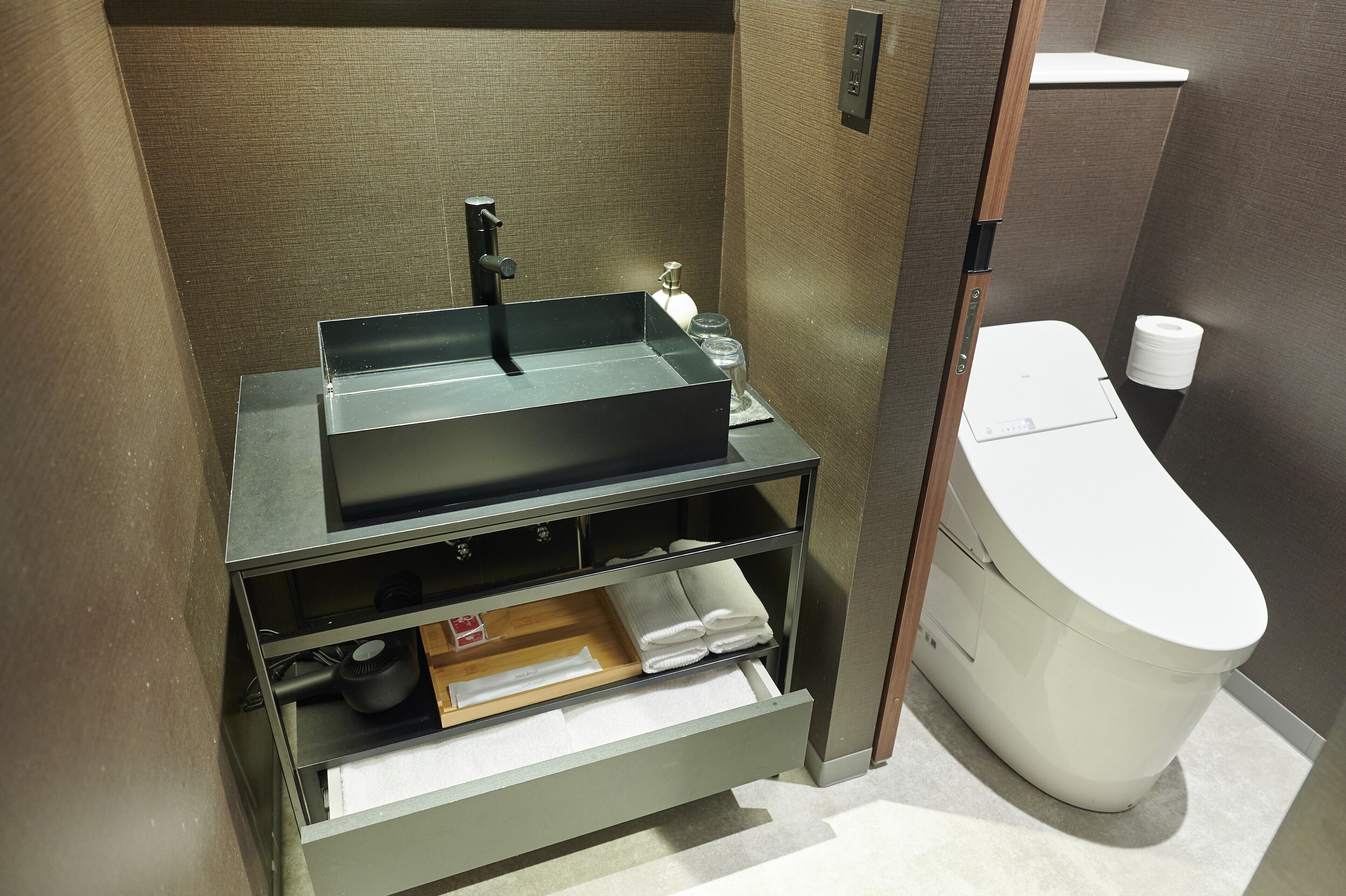 Ein Badezimmer mit einem modernen Waschbecken, einer Toilette und einem Handtuchhalter.