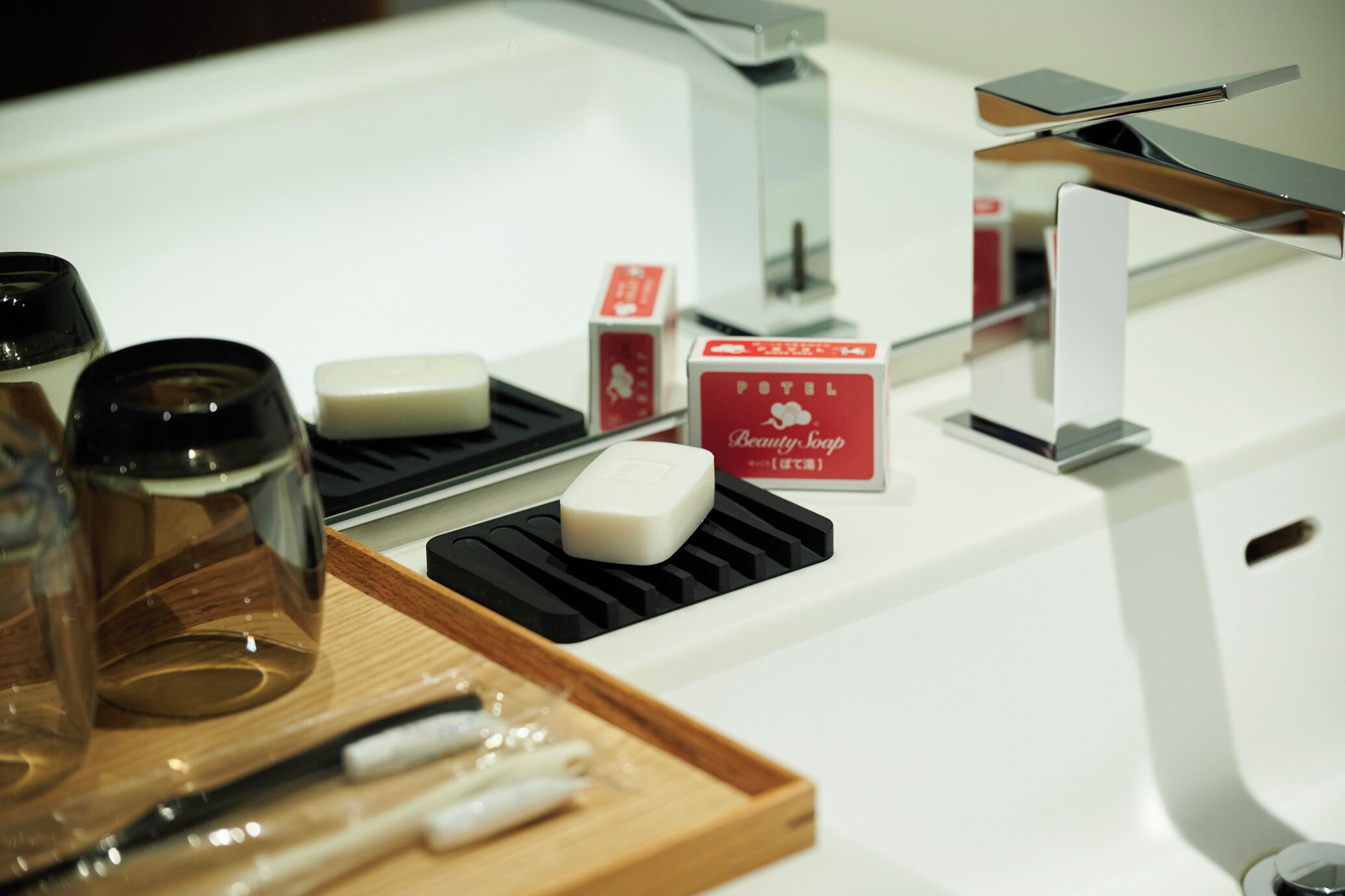 A bathroom with a white sink, a soap dispenser, and a tray with a toothbrush and toothpaste.