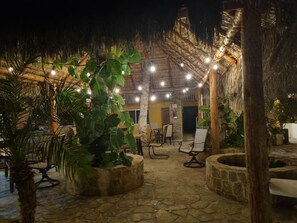 An outdoor patio area with stone flooring, several chairs, and potted plants. - Hotel alcatraz (Comondu)