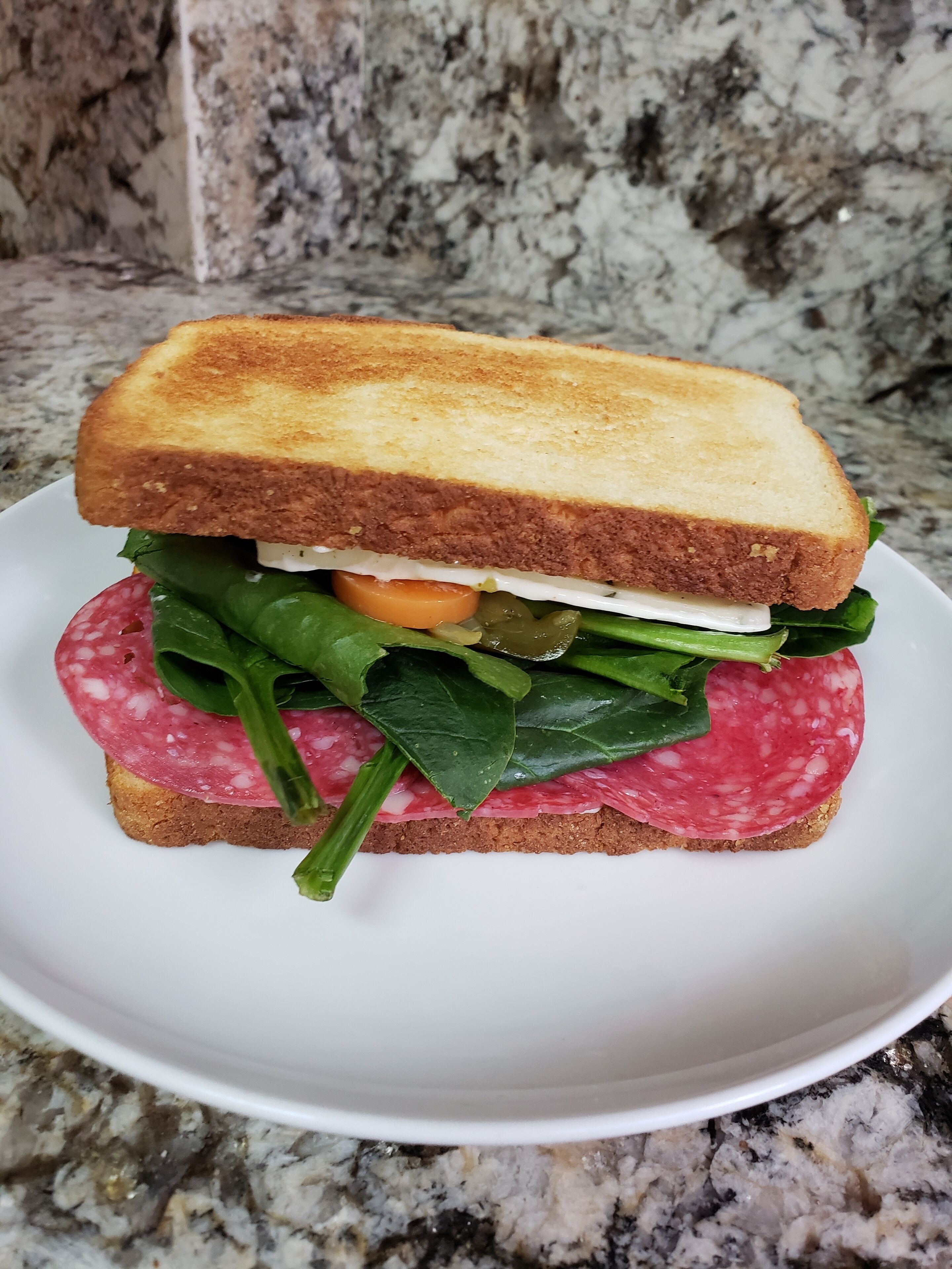 A sandwich with multiple layers of ingredients on a white plate.