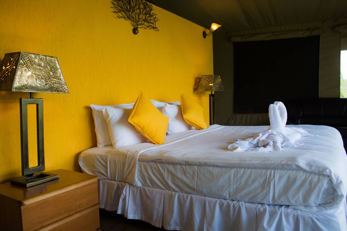 Una habitación de hotel con una cama, dos lámparas de noche, una mesita de noche y un adorno en la pared.
