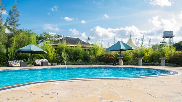 Una piscina con baldosas de piedra, sillas de descanso y sombrillas.