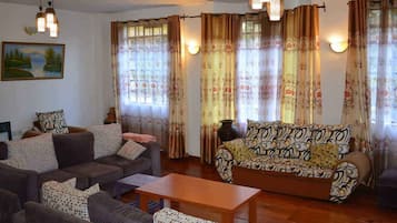 Sala de estar com dois sofás, uma mesa de centro e cortinas estampadas.